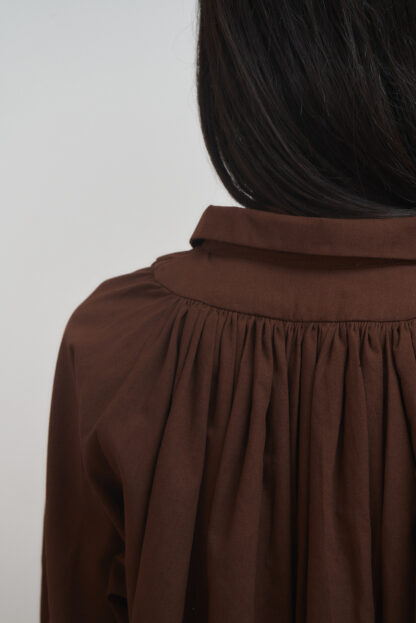 closeup on gathered details on the back of brown shirt dress.