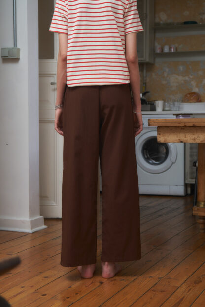 Back view of Nella pants brown wide legged trouser with an extra long contrast-color belt. Woven organic cotton.