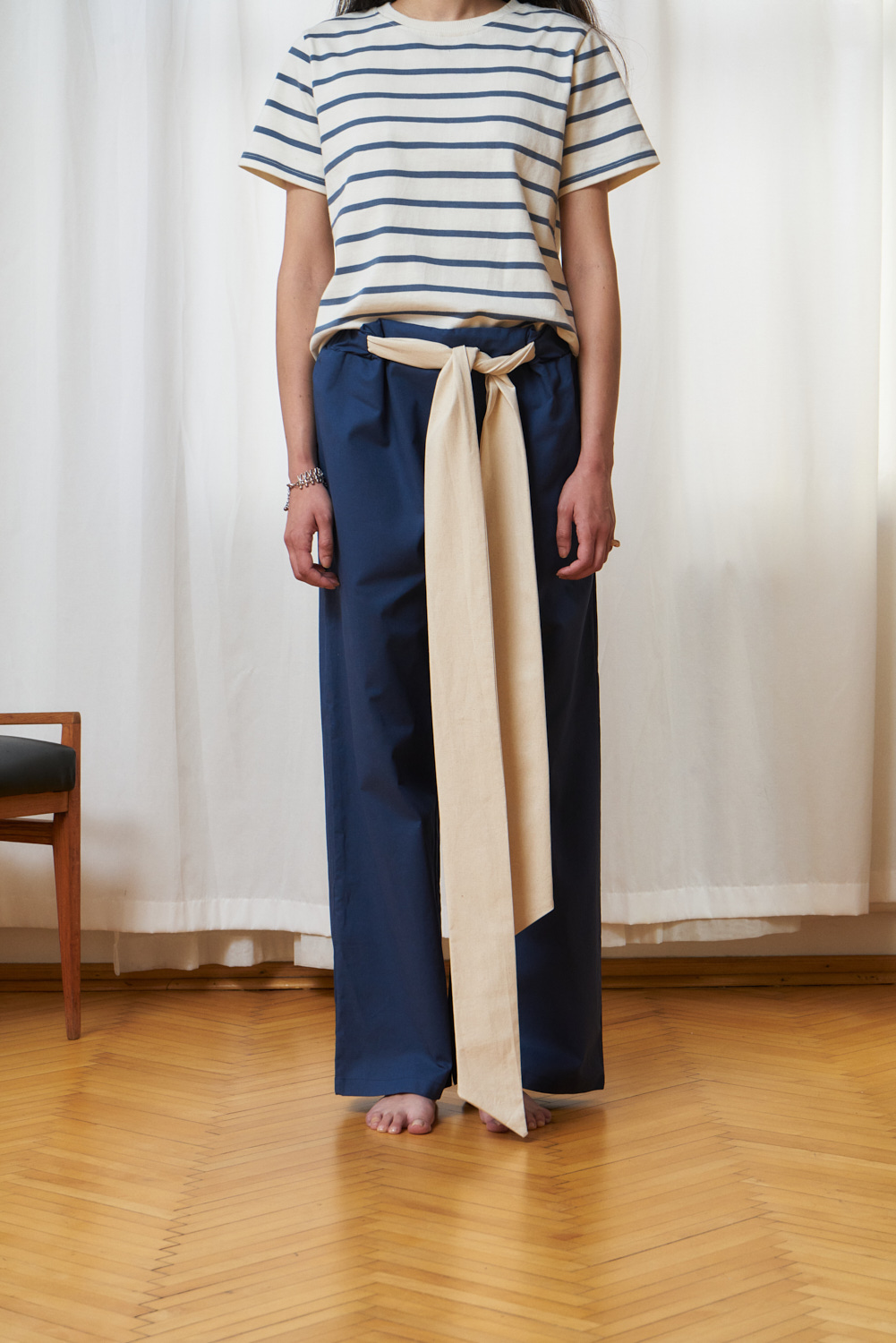 Nella pants dark blue wide legged trouser with an extra long contrast-color belt. Woven organic cotton.