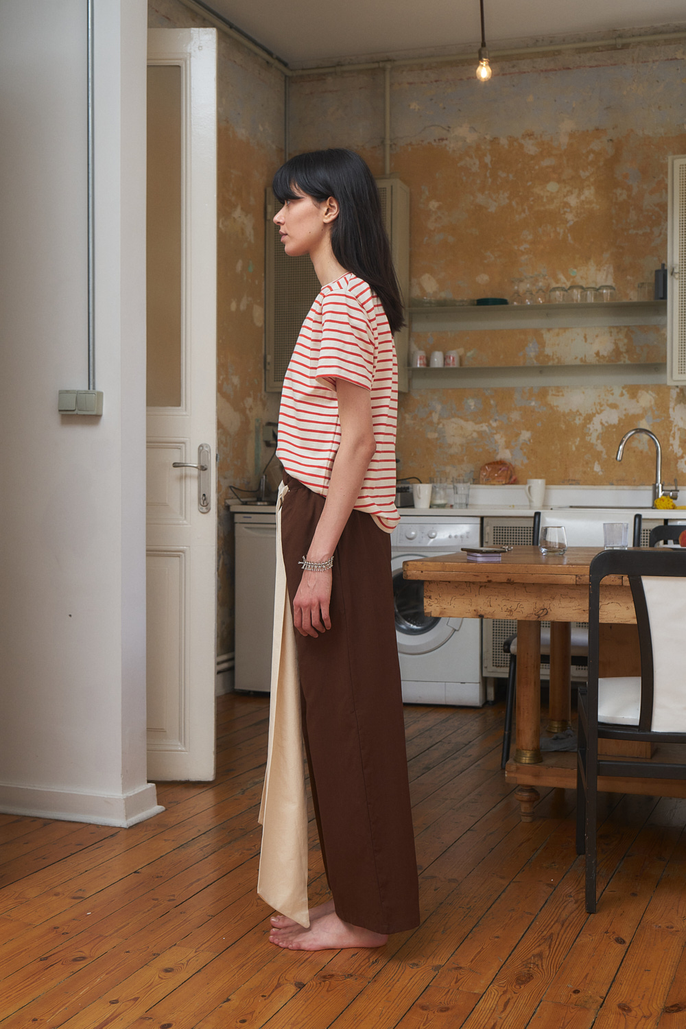 Side view of Nella pants brown wide legged trouser with an extra long contrast-color belt. Woven organic cotton.
