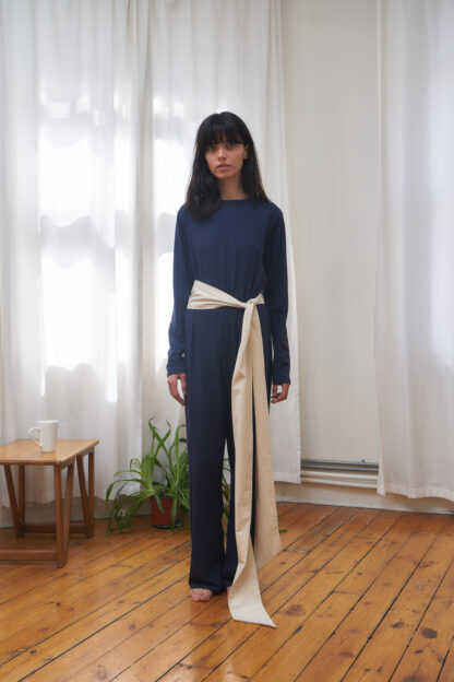 Ahu jumpsuit dark blue jersey jumpsuit with long legs and an ecru contrasting belt. Long sleeves and crewneck.