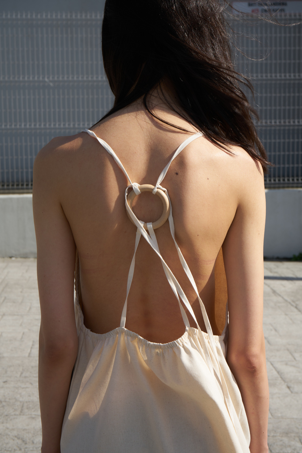 Eba halter dress open back and tie-strings around a small wooden ring. Closeup detailed view.